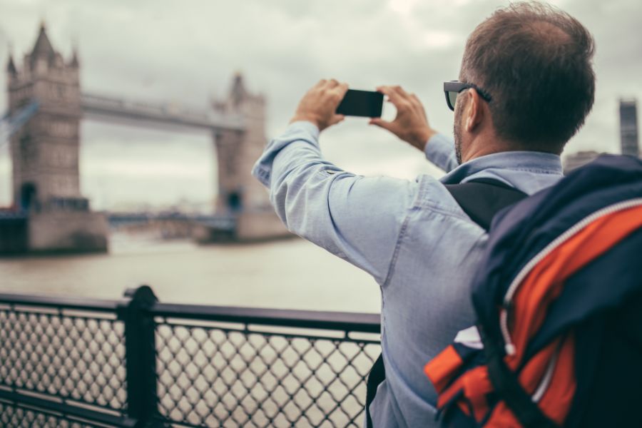 A man taking a picture of the Tower Bridge in London