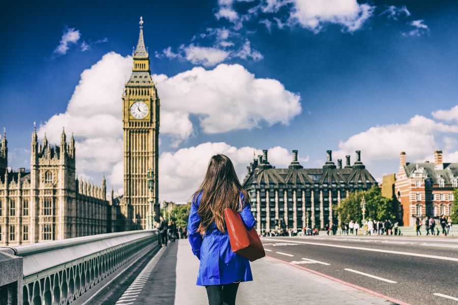 A tourist exploring the streets of London, walking across a bridge headed towards Big Ben.