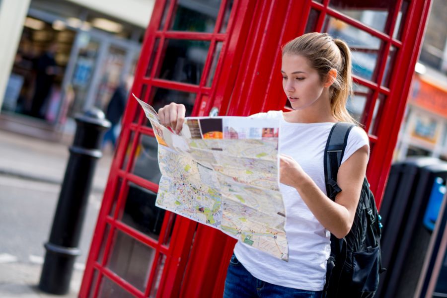 A tourist checking a physical London map, which you wouldn't have to worry about, if you purchase our London itinerary