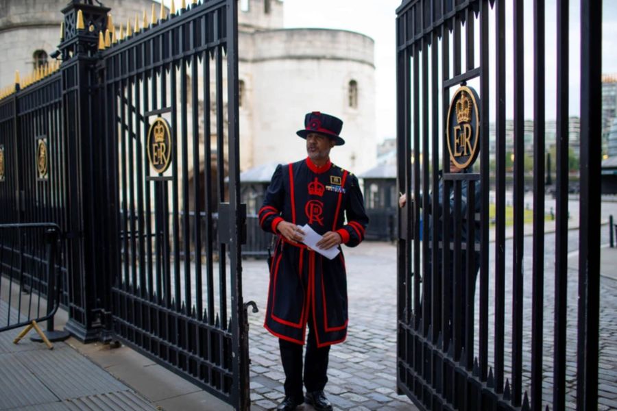 Yeoman Warder Beefeater in ceremonial red and black uniform standing at the gates of the Tower of London