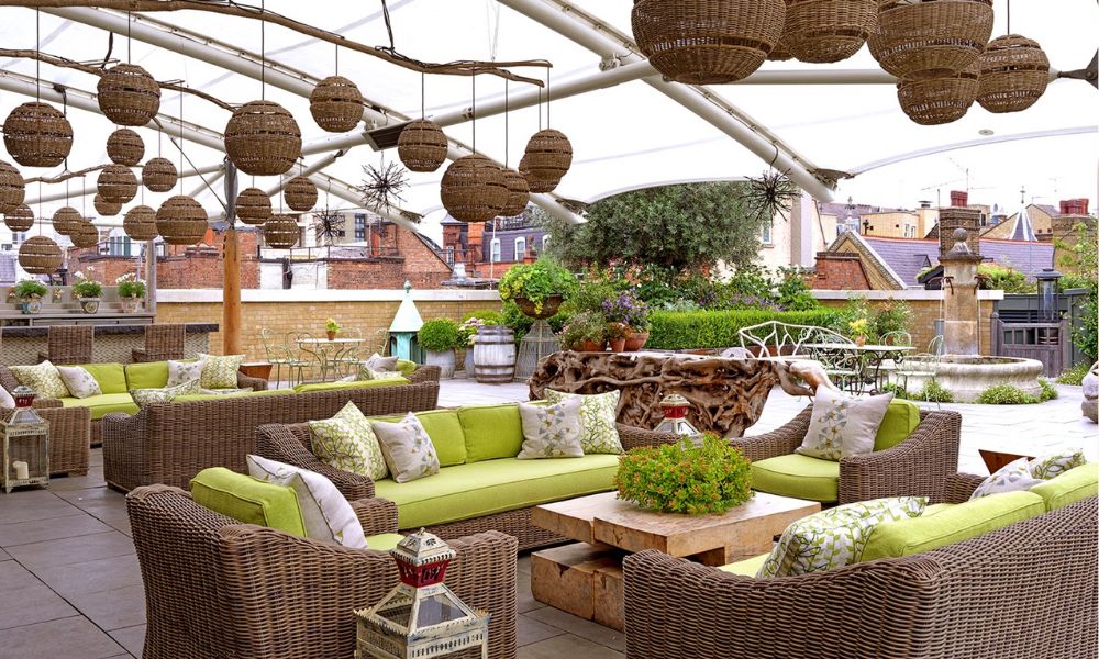 This is an image of a rooftop bar with boho furniture and green accents.