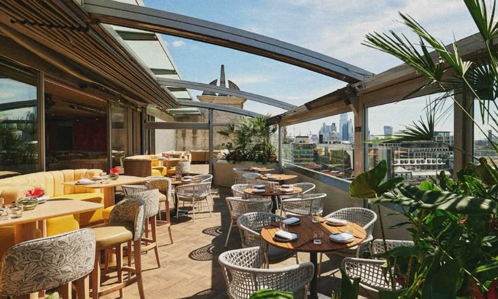 This is an image of an open-air rooftop with lots of dining tables and plants.