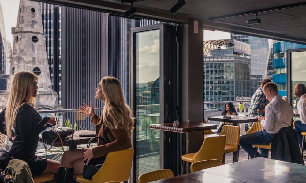 This is an image of a rooftop bar with views of Bank and other high rise buildings in London.