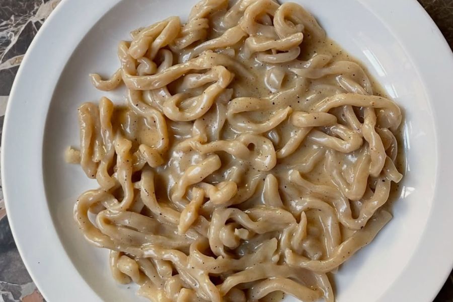 This is an image of a cacio e pepe pasta plate with saucy sauce.