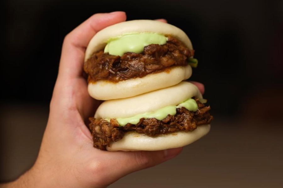 This is an image of a bao bun with meaty and saucy fillings.