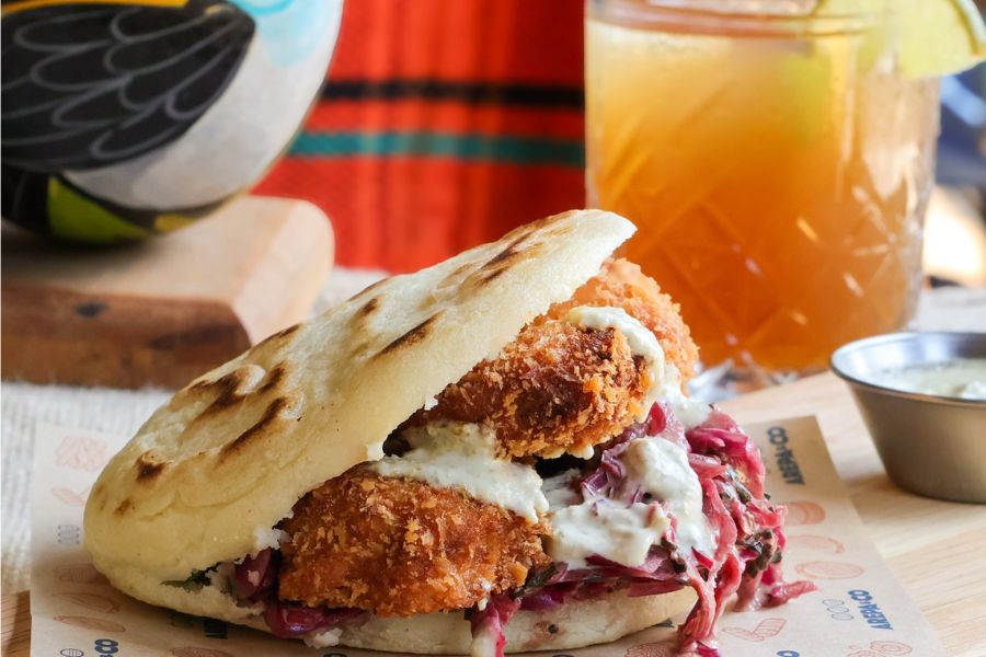 This is an image of a fish arepa with a lemonade on the side, which is the restaurant's weekday lunch deal.