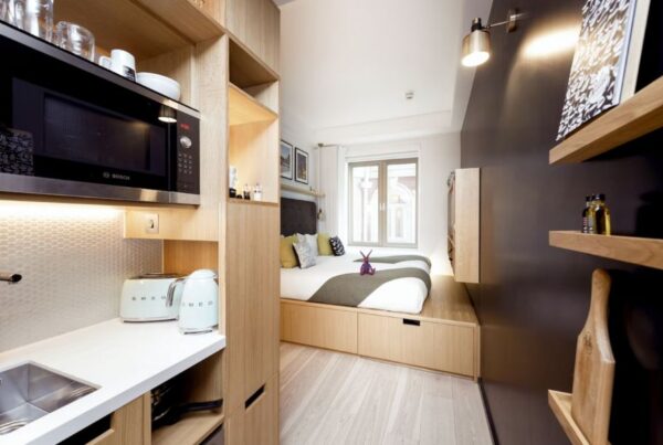 This is an image of a double bed in the corner and a kitchenette on the way in.