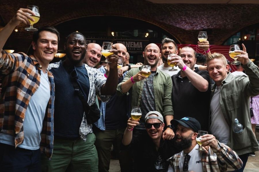 This is an image of a group of men holding up their beers smiling.