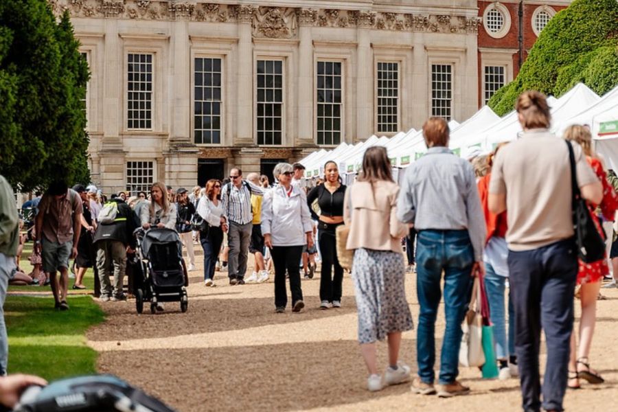 This is an image of a market in Hampton Court Palace with stalls set up and people milling around.