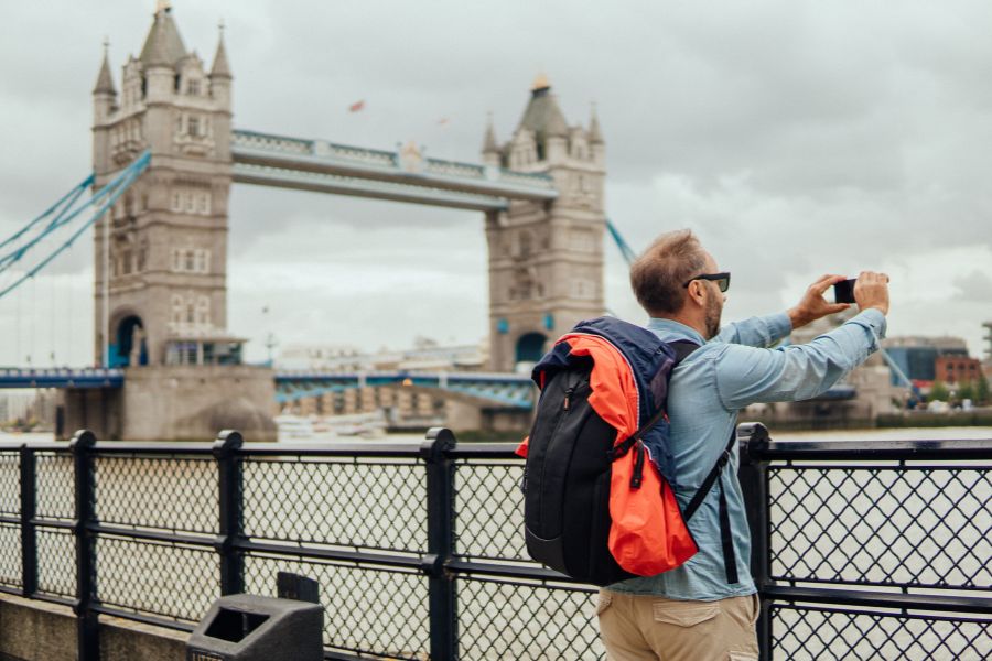 A tourist taking pictures by the Thames, courtesy of a planned London itinerary