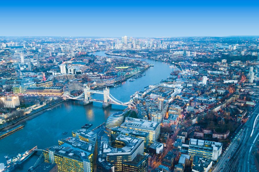 Aerial view of London at dusk showing Tower Bridge, the River Thames and the city skyline stretching towards Canary Wharf