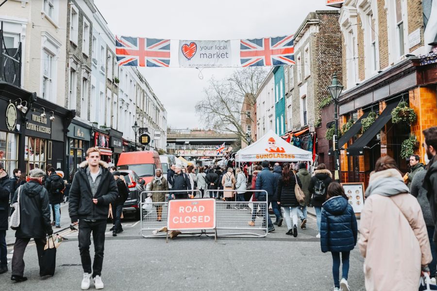 Busy Portobello Road Market in Notting Hill with Union Jack flags overhead and crowds of shoppers on a winter day