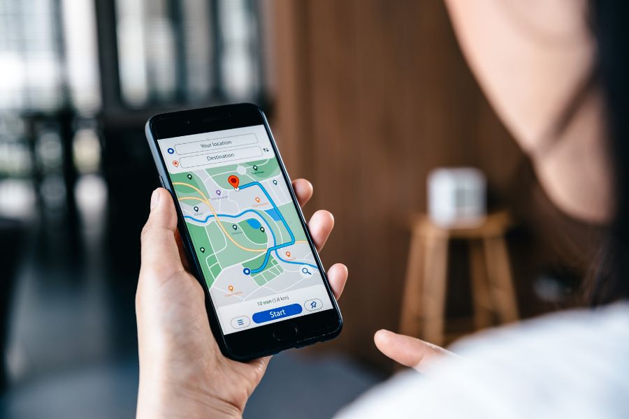 Person holding a smartphone displaying a navigation map with a route highlighted in blue