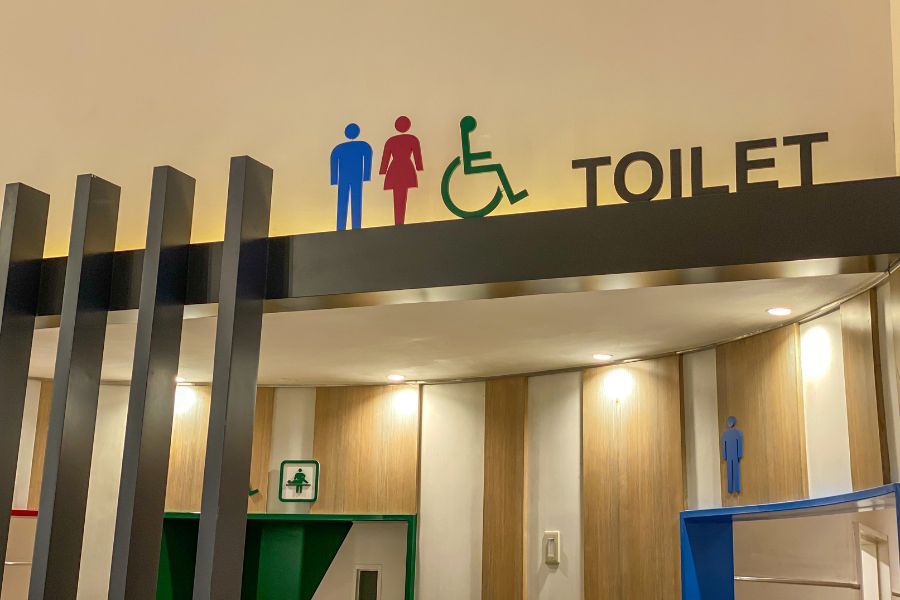 Public toilet entrance with male, female and wheelchair accessibility symbols above the doorway.