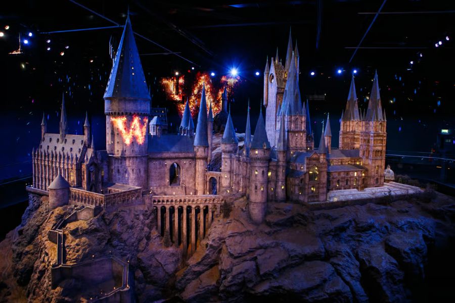 The large-scale model of Hogwarts Castle dramatically lit against a dark background at the Warner Bros. Studio Tour in Watford
