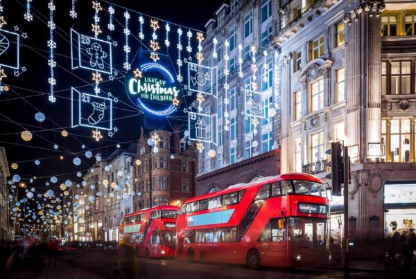 This is an image of a bus driving down Oxford Street with Christmas lights out everywhere.