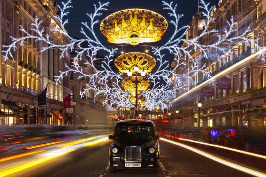 A black cab driving through the Christmas lights in London.