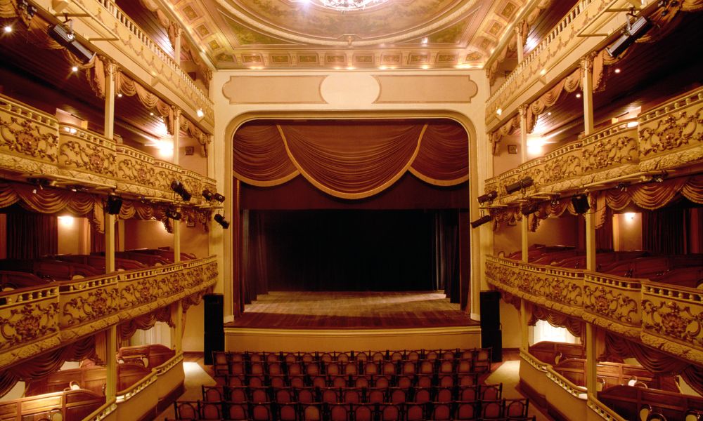 This is an image of an old theatre with plenty of seats and balcony style arrangements.