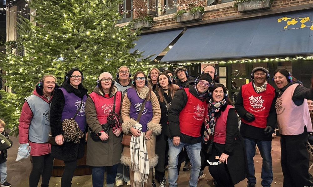 This is an image of a group of people wearing silent disco headphones standing in front of a Christmas tree