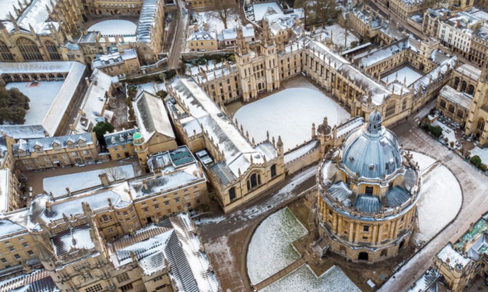 This is an image of a snowy, beautiful UK town with brick buildings from a birdseye view.
