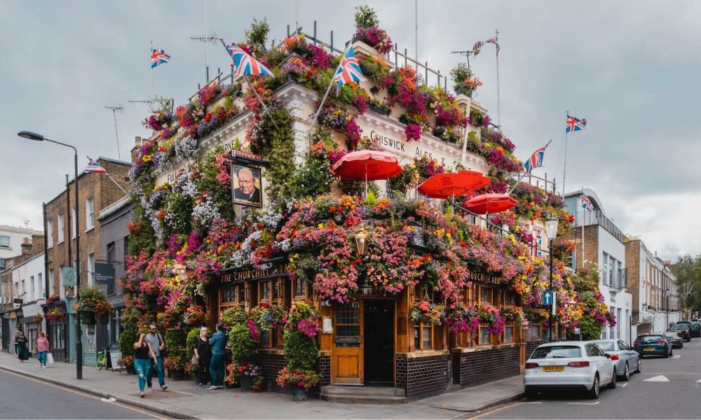 This is an image of a big pub with flowers around the front and and florals and greenery.