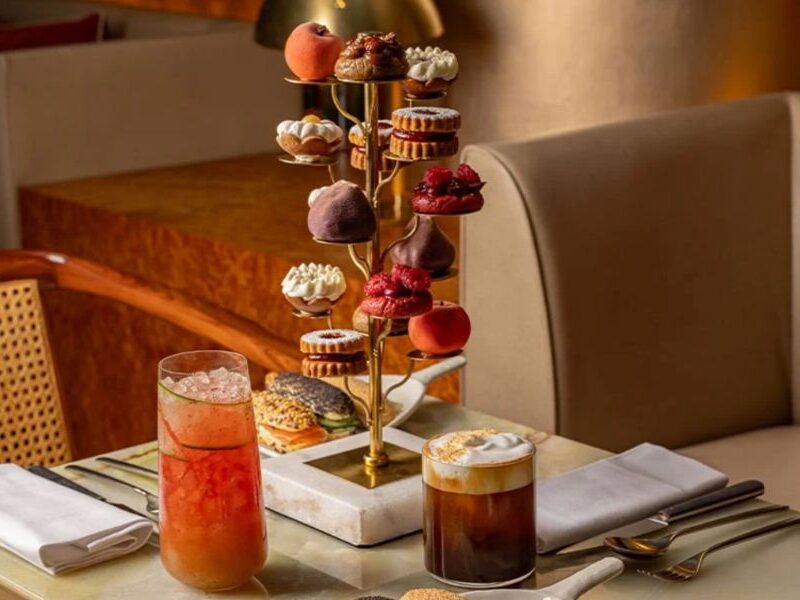 Unique afternoon teas in London: This is an image of a tiered stand with delicious drinks and artsy cakes.