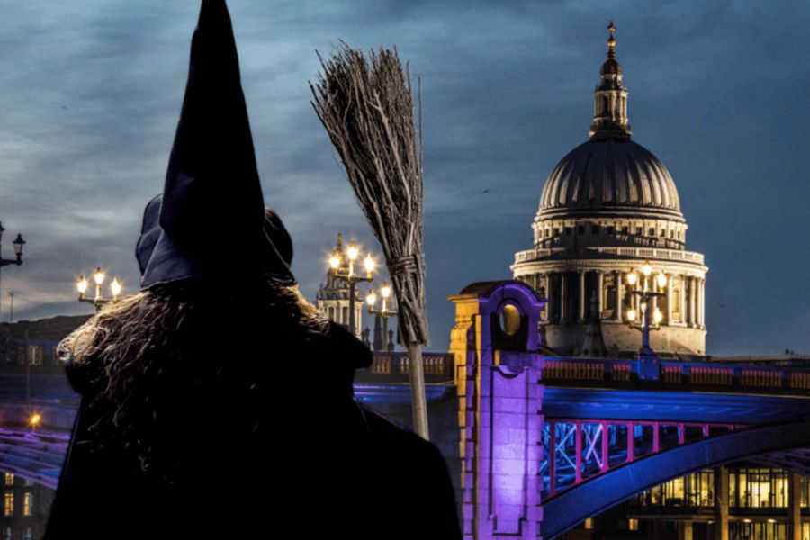 This is an image of a tour guide dressed up as a witch with a view of St Paul's Cathedral behind it.