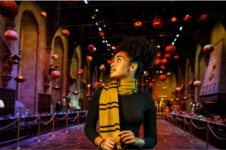 This is an image of a girl with the Great Hall from Harry Potter behind her. It is decorated for Halloween.