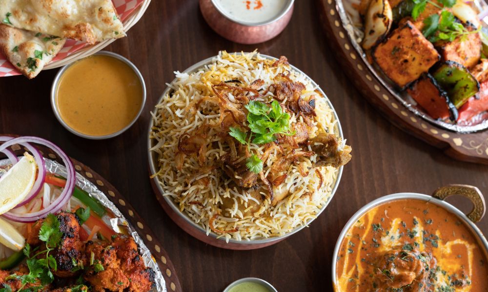 This is an image of a table full of curries, biriyani and other amazing Indian food.