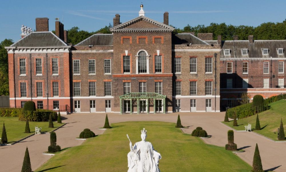 This is an image of Kensington Palace with all its bricks and gardens in view. There is also a statue on the centre grass.