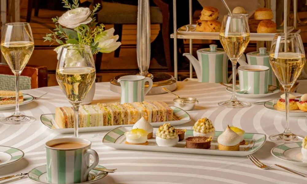 This is an image of an afternoon tea spread at Claridge's with a bunch of mini sandwiches on the table and flutes of champagne.