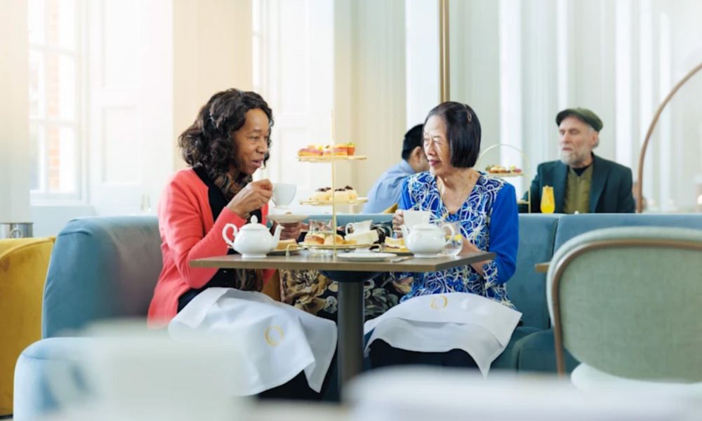 This is an image of two ladies sitting at a table with an afternoon tea spread on it.