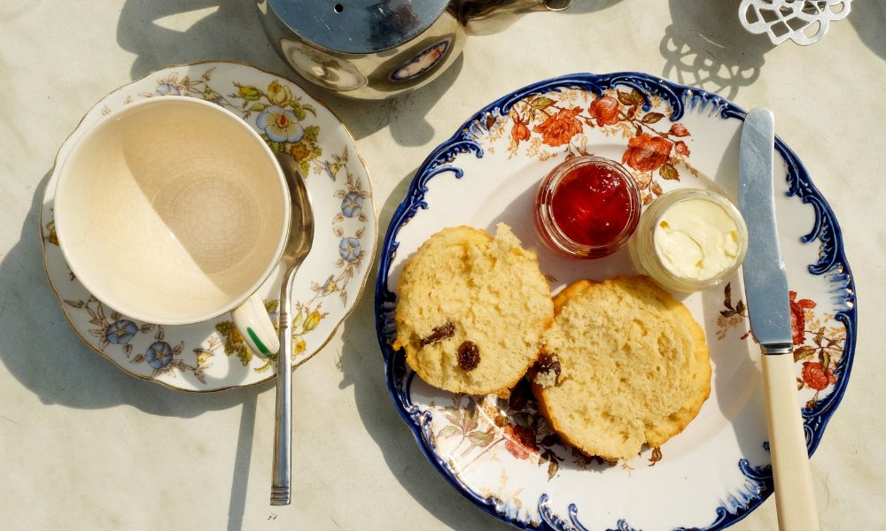 This is an image of scones on a plate with jam and cream pots.