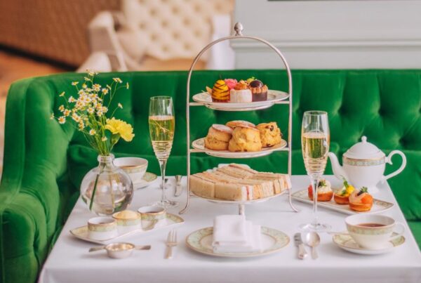 This is an image of a nice afternoon tea spread with a three-tiered cake stand, teapot and champagne flutes.