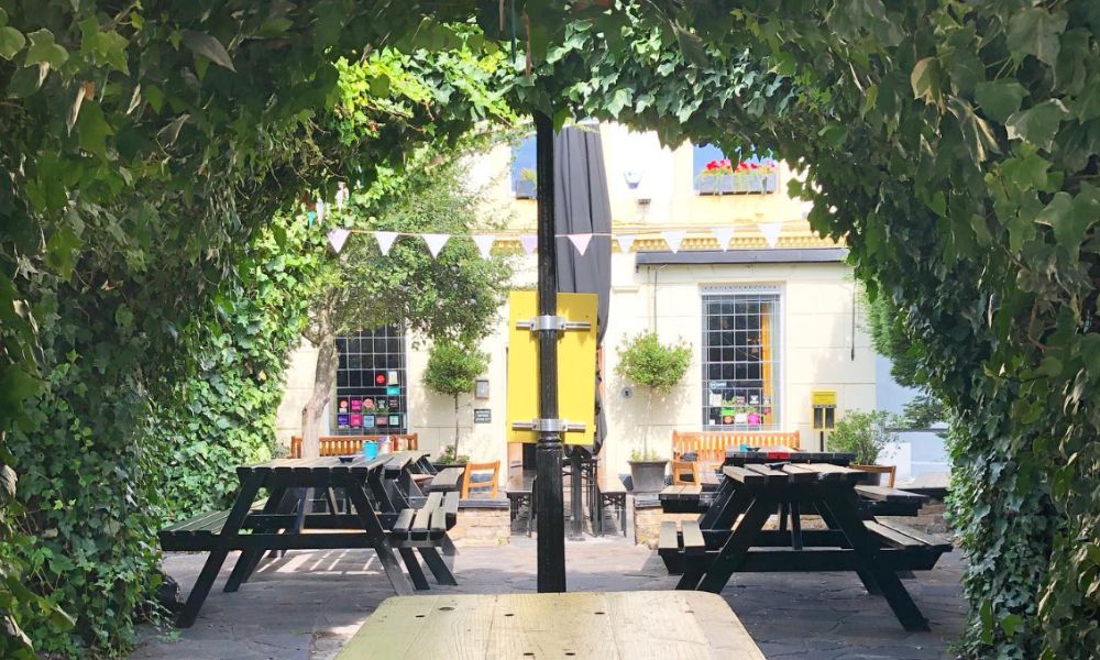 This is an image of a beer garden with long park tables lining the courtyard.