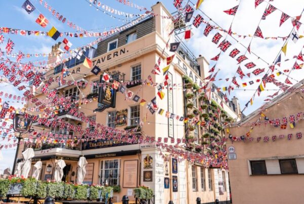 This is an image of a pub on the water with a bunch of flags being tied up around the building.