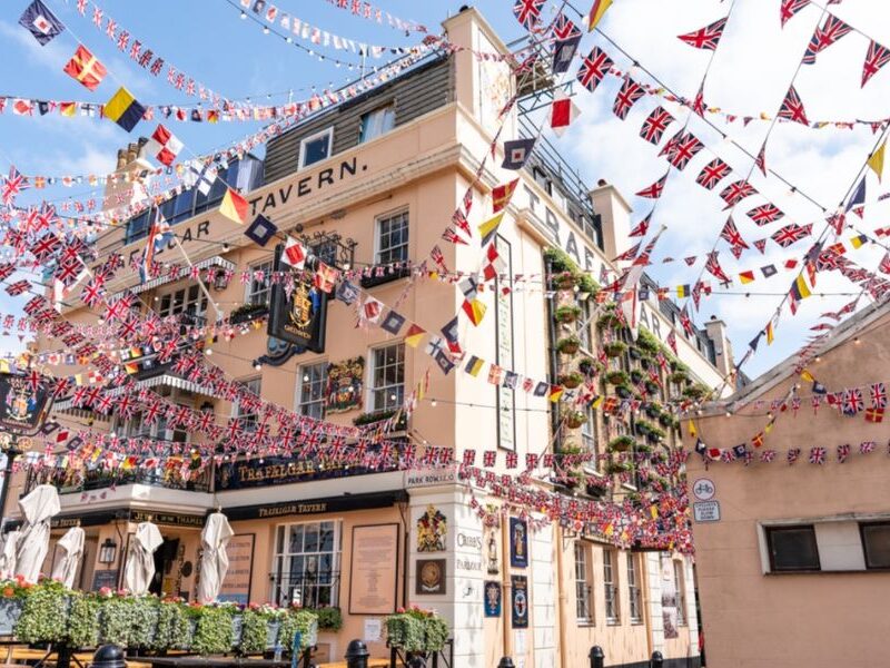This is an image of a pub on the water with a bunch of flags being tied up around the building.