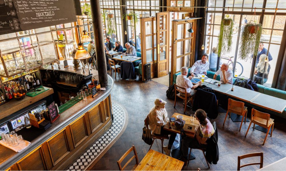 This is a birdseye image of the ground floor of a pub with a bar and a few people sitting up at all the tables.