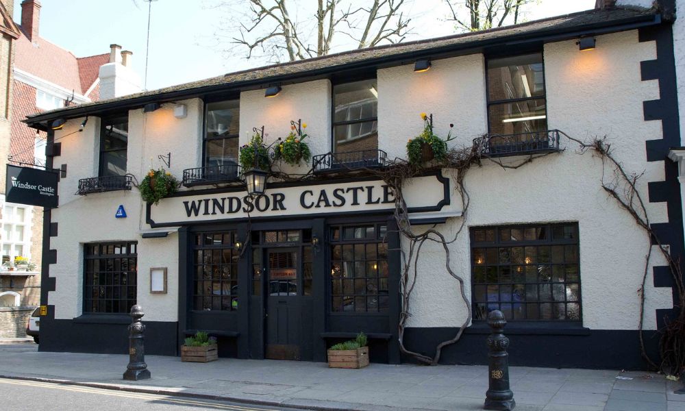 This is an image of the exterior of The Windsor Castle with plants and lighting surrounding it.