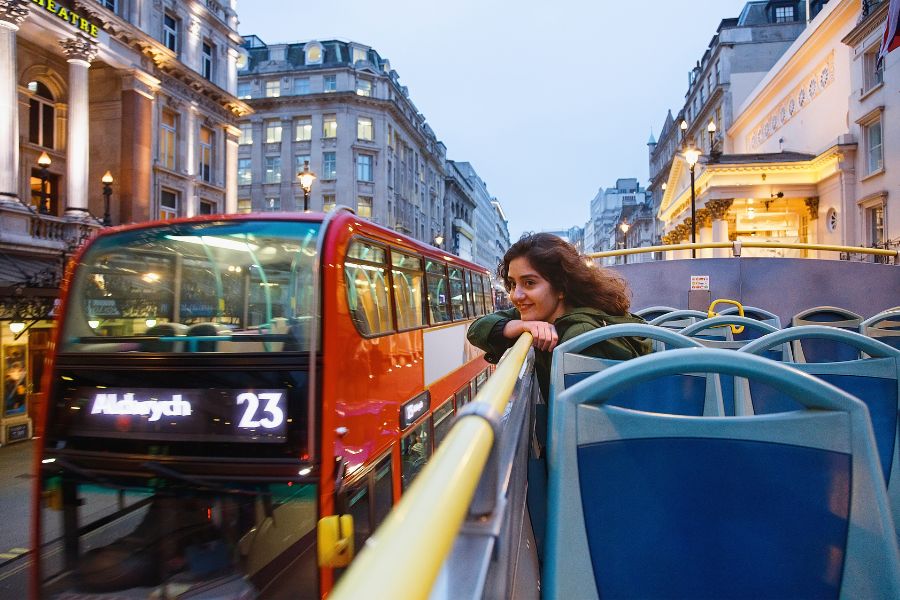 A woman enjoying the London breeze on the upper deck of a bus 