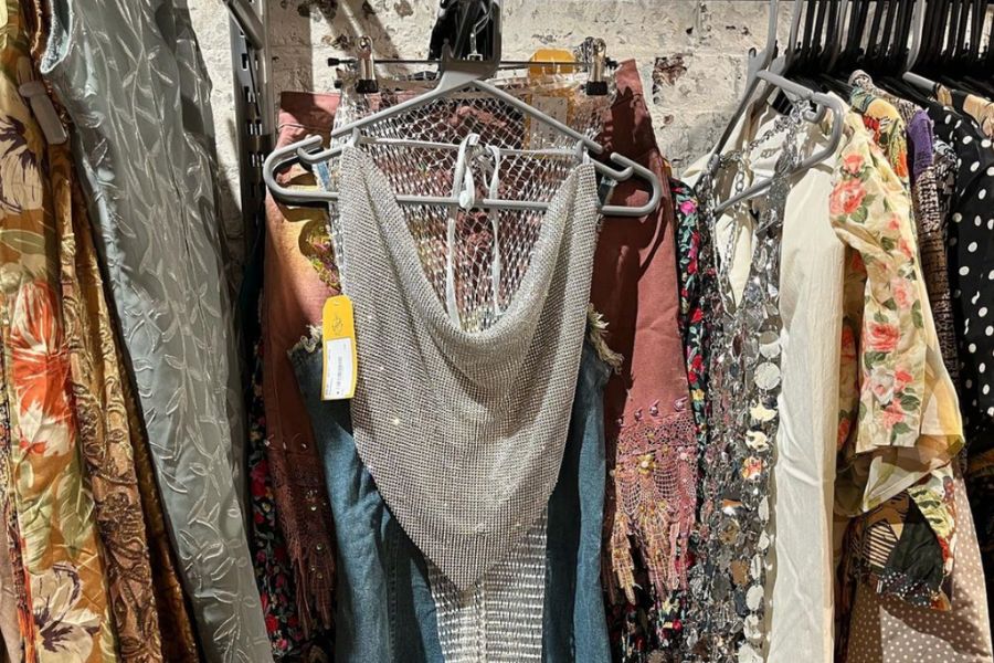 This is an image of a rack full of clothes with a sequin silver top showcased at the front.