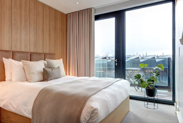 This is an image of a sleek hotel bedroom with big windows and a muted palette.