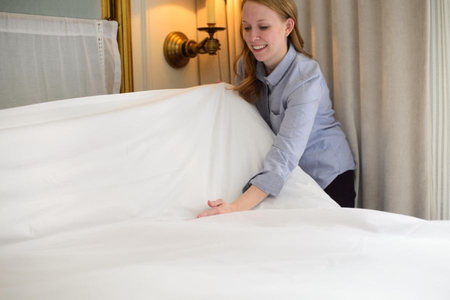 An in-house staff making the hotel bed in the morning