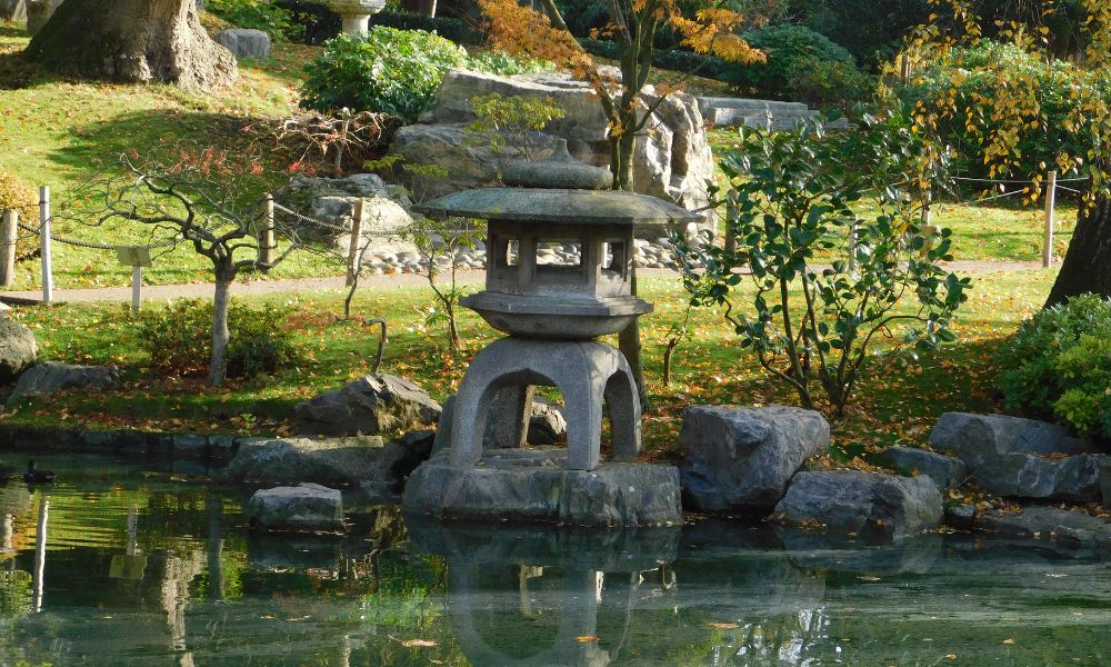 This is an image of a Japanese Garden with a little mini pagoda and rocks near a little garden lake.