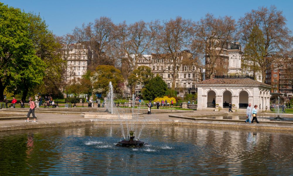 This is an image of a beautiful part of Hyde Park with a water fountain and trees.