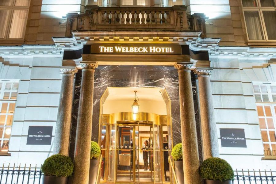 This is an image of the front of the hotel with gold detailing at the entrance and the classic white house panelling.