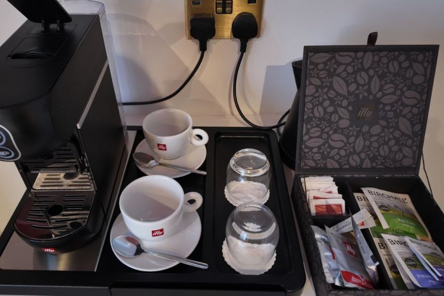 This is an image of a tea and coffee station with teas, mugs and saucers, plus a coffee pod machine.