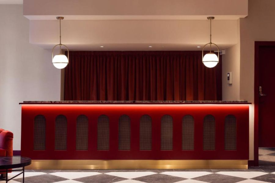 This is an image of a check-in desk that is red with lights above it. It's very minimalist because nothing else is around.