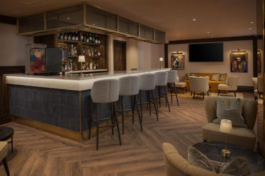 This is an image of the dining area in The Welbeck, where a bar is featured with chairs and tables.