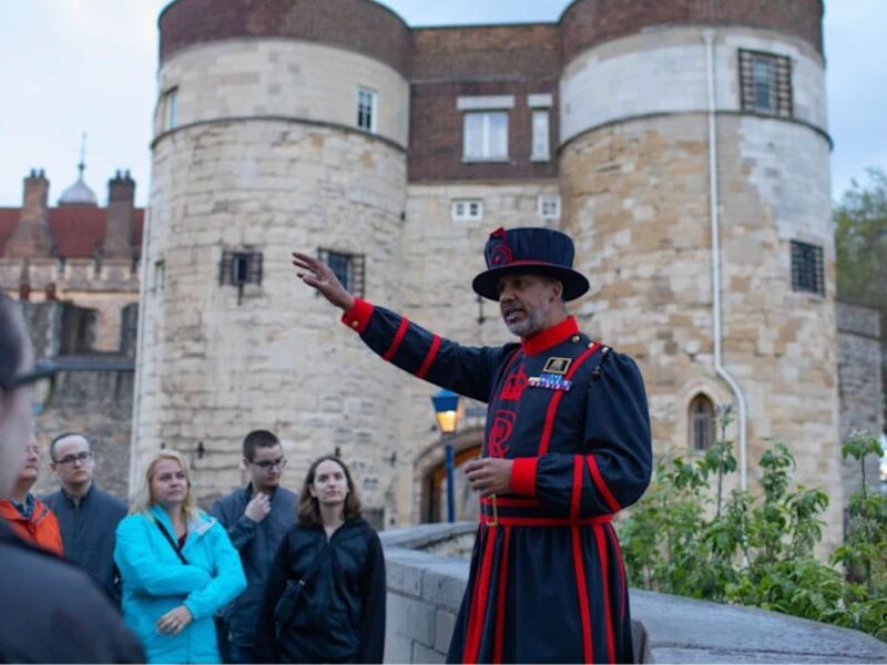 This is an image of the Yeoman tour leader showing a tour group the tower of London in early eve.